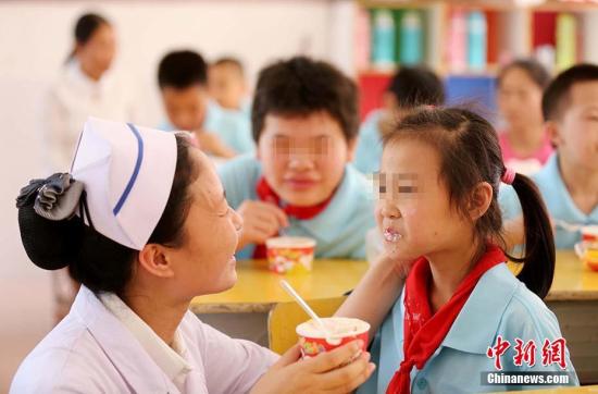 特殊教育学校，一名医护人员在喂学生吃蛋糕(资料图)。 谭凯兴 摄